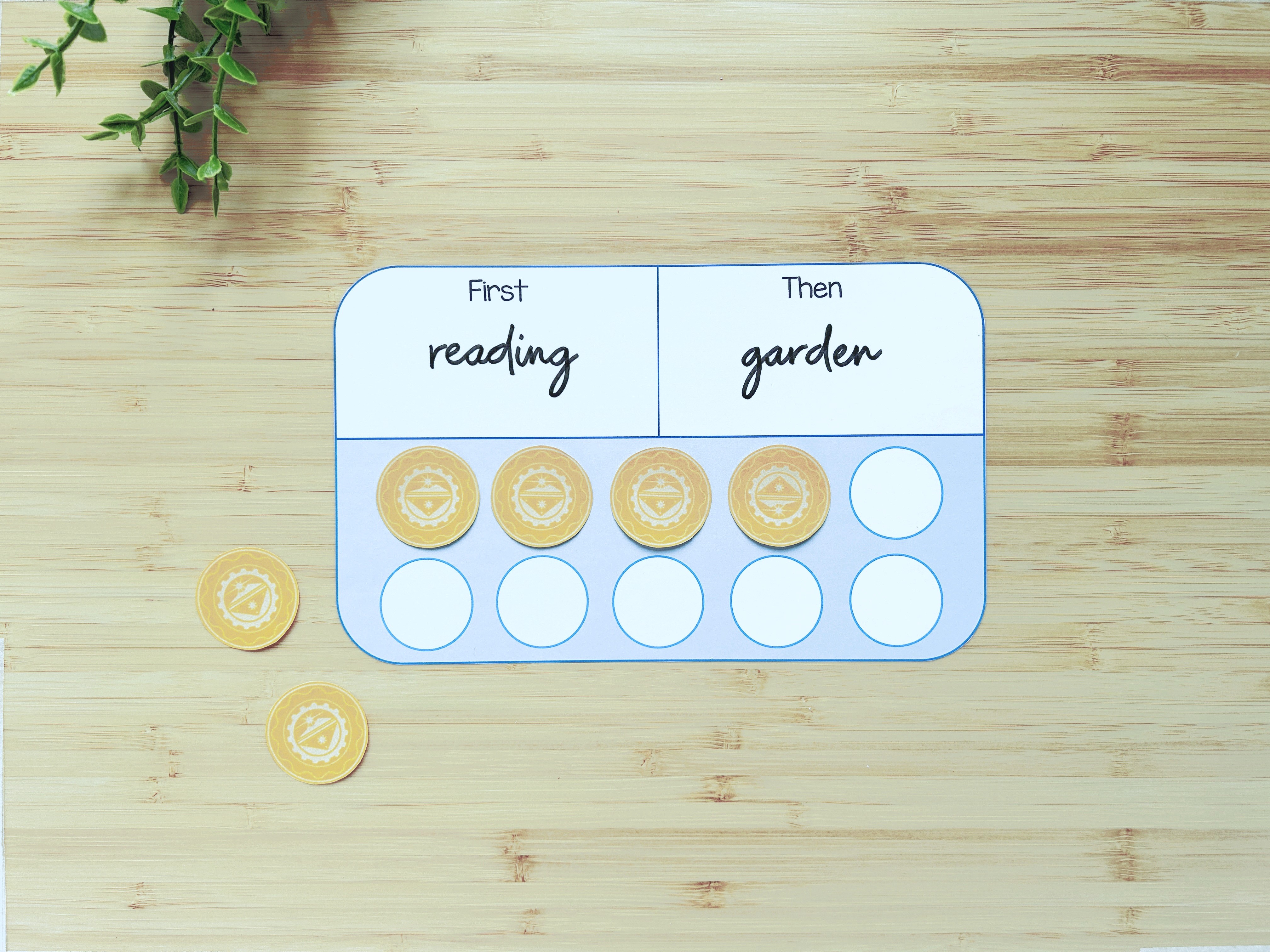 A First and Then board on a wooden table showing reading first, then garden, with token circles below